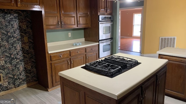 kitchen featuring black gas stovetop, a center island, and stainless steel double oven