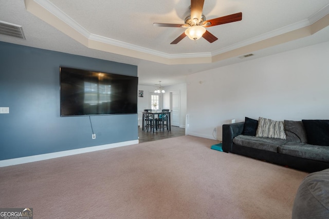 carpeted living room with ornamental molding, a raised ceiling, and ceiling fan with notable chandelier