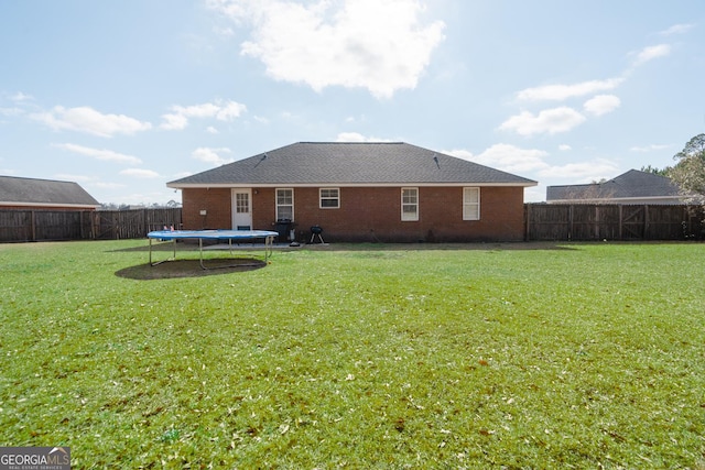 rear view of house with a trampoline and a lawn