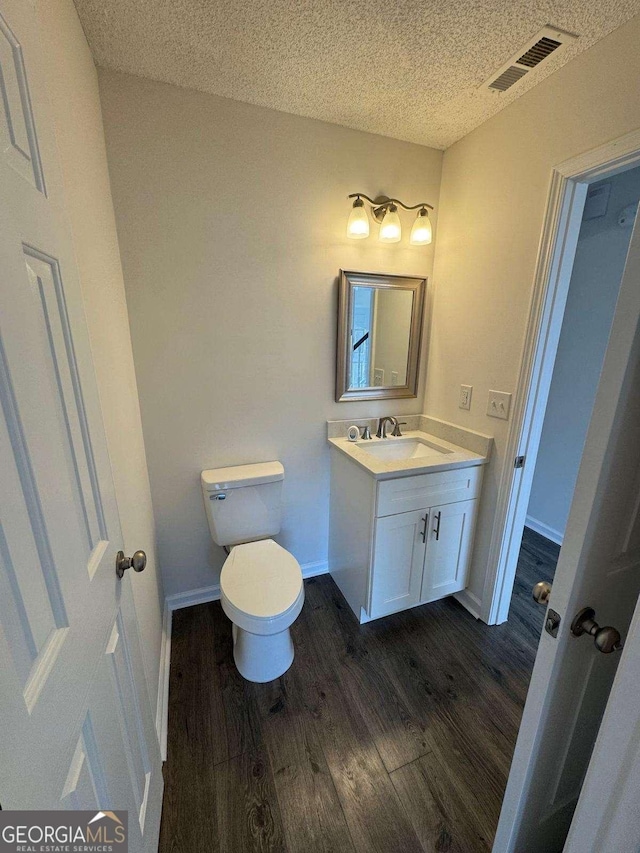 bathroom with vanity, hardwood / wood-style floors, a textured ceiling, and toilet