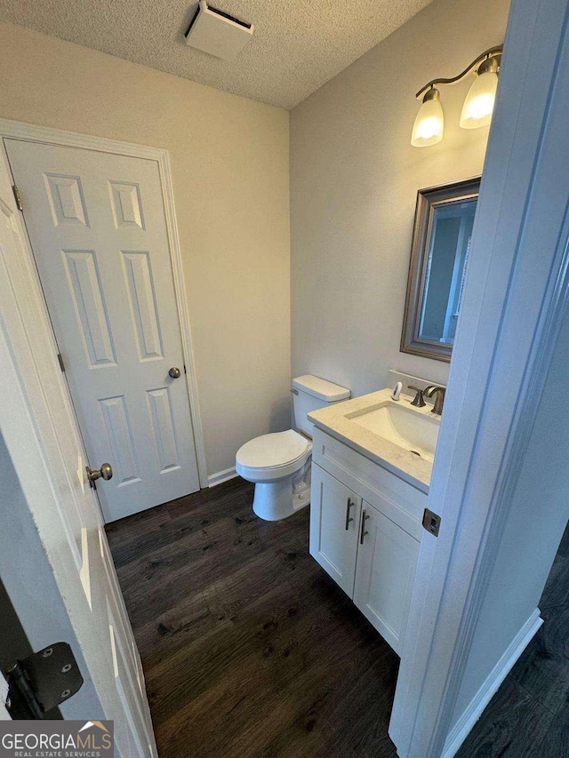 bathroom featuring vanity, hardwood / wood-style floors, a textured ceiling, and toilet