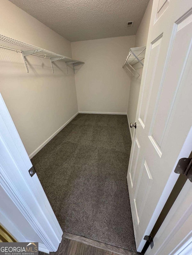 walk in closet featuring dark carpet