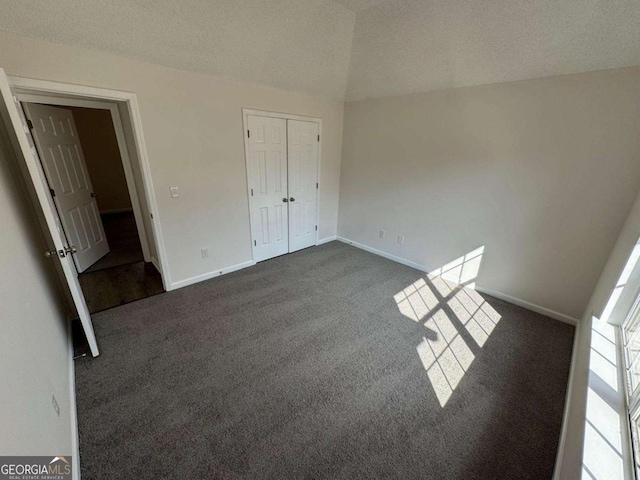 unfurnished bedroom featuring dark colored carpet, a textured ceiling, and a closet