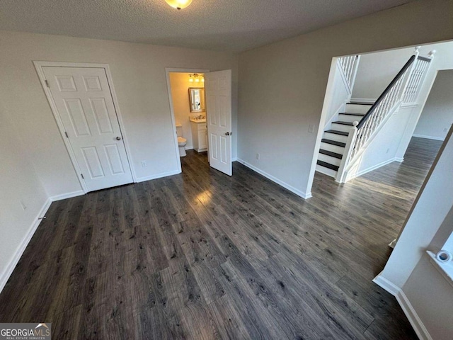 unfurnished bedroom featuring a textured ceiling and dark hardwood / wood-style flooring