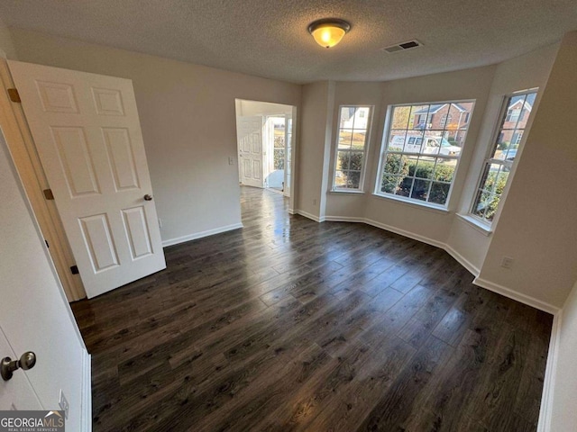 spare room with dark hardwood / wood-style floors and a textured ceiling