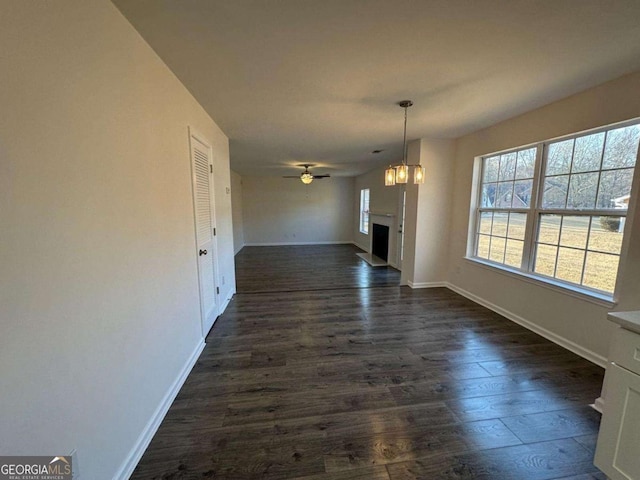 unfurnished living room featuring ceiling fan and dark hardwood / wood-style flooring