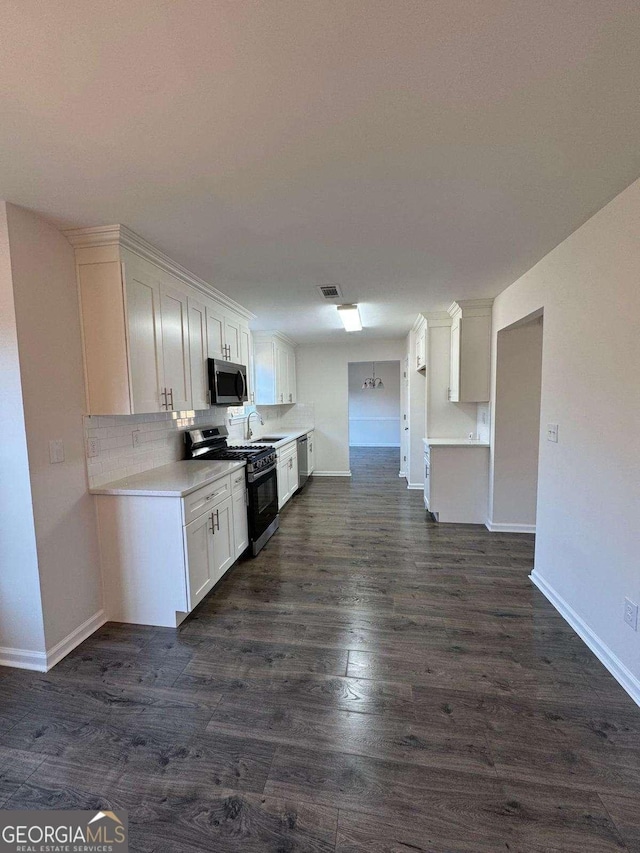 kitchen featuring appliances with stainless steel finishes, backsplash, white cabinets, and dark hardwood / wood-style flooring