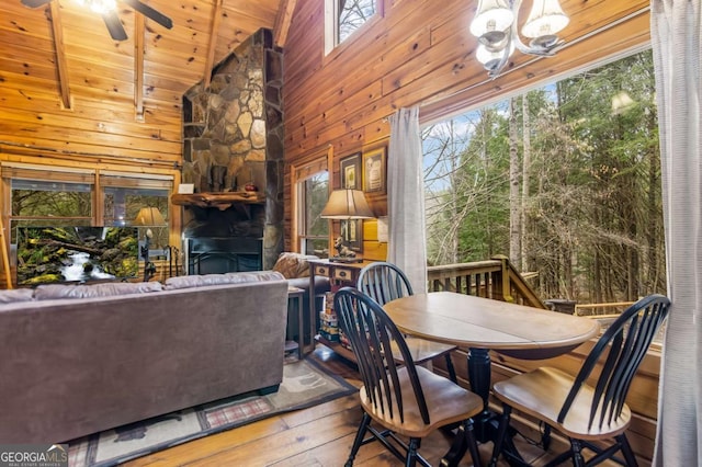 dining area with hardwood / wood-style flooring, ceiling fan with notable chandelier, wooden ceiling, and wood walls