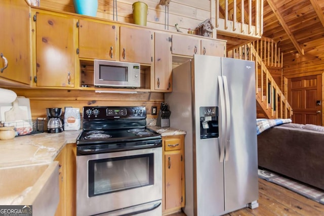 kitchen featuring stainless steel appliances, wooden ceiling, wooden walls, and light hardwood / wood-style flooring