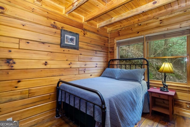 bedroom with dark hardwood / wood-style flooring, wooden walls, wooden ceiling, and beam ceiling