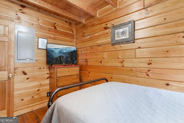 bedroom featuring hardwood / wood-style floors, electric panel, wooden ceiling, beamed ceiling, and wood walls