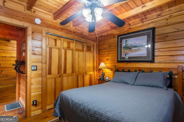 bedroom featuring hardwood / wood-style flooring, wooden walls, wooden ceiling, and beamed ceiling