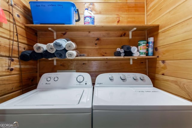 washroom featuring washing machine and dryer and wood walls