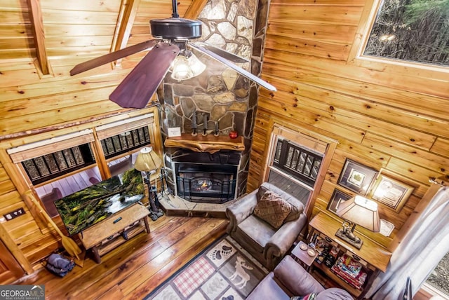 living room with wood walls, hardwood / wood-style floors, sink, and a wood stove