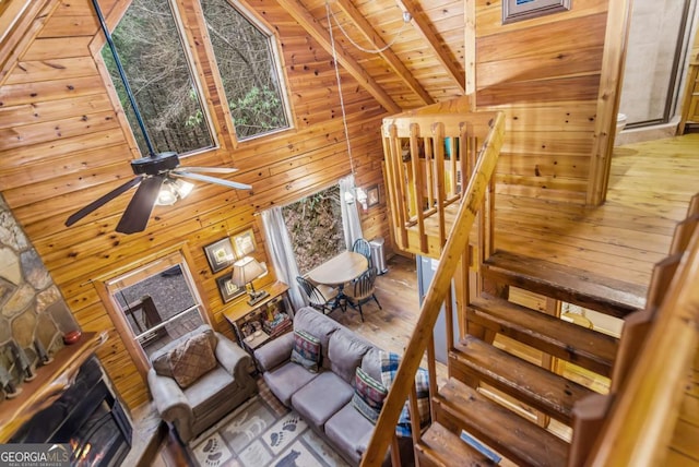 living room featuring wooden walls, high vaulted ceiling, wood-type flooring, wooden ceiling, and beamed ceiling