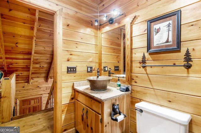 bathroom featuring wooden walls, vanity, wood ceiling, toilet, and beam ceiling