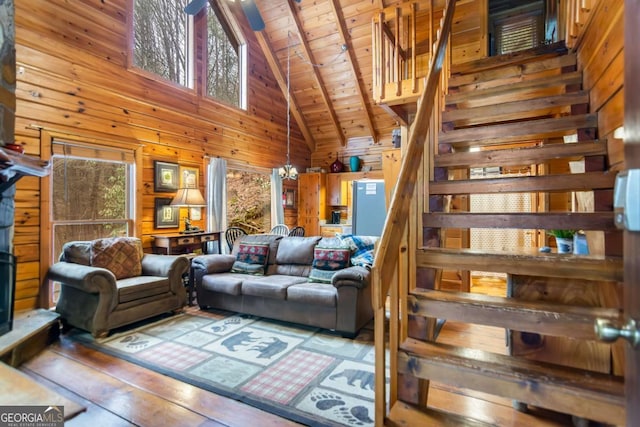 living room featuring wood walls, an inviting chandelier, high vaulted ceiling, wooden ceiling, and beam ceiling