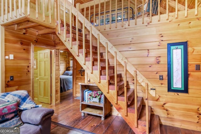 stairway featuring hardwood / wood-style flooring and wooden walls