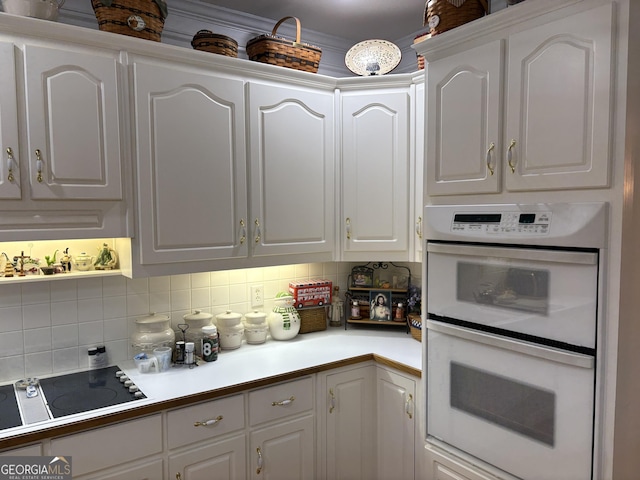 kitchen featuring white cabinetry, black electric stovetop, decorative backsplash, and white double oven