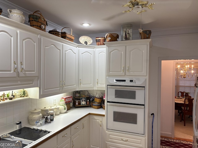 kitchen with white cabinetry, tasteful backsplash, a chandelier, black electric cooktop, and white double oven