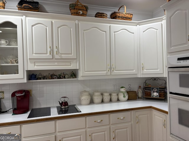 kitchen with decorative backsplash, black electric stovetop, white double oven, and white cabinets