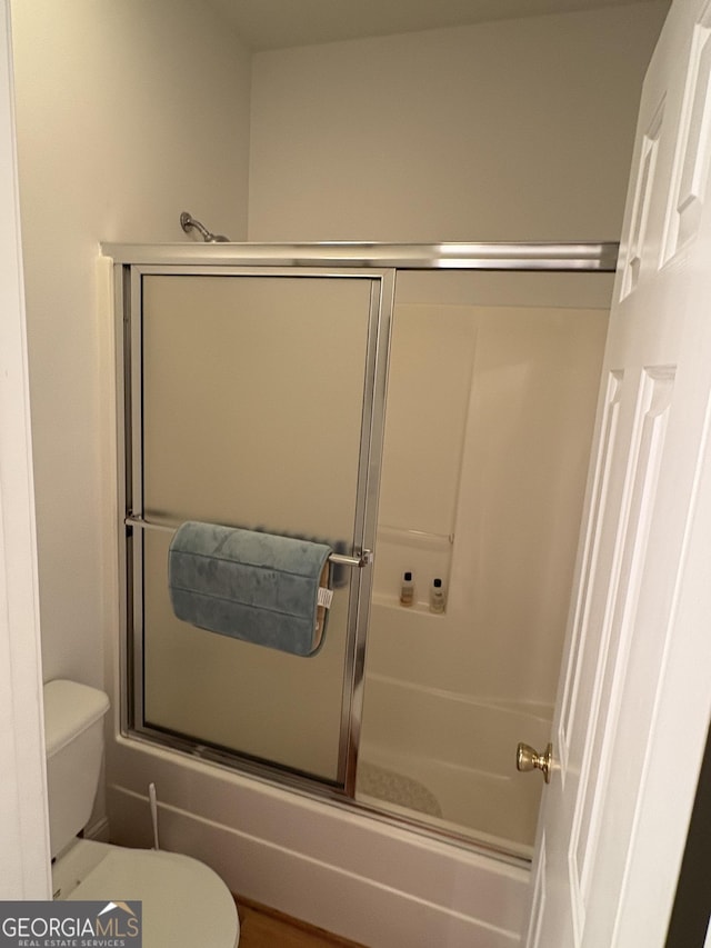 bathroom with toilet and combined bath / shower with glass door