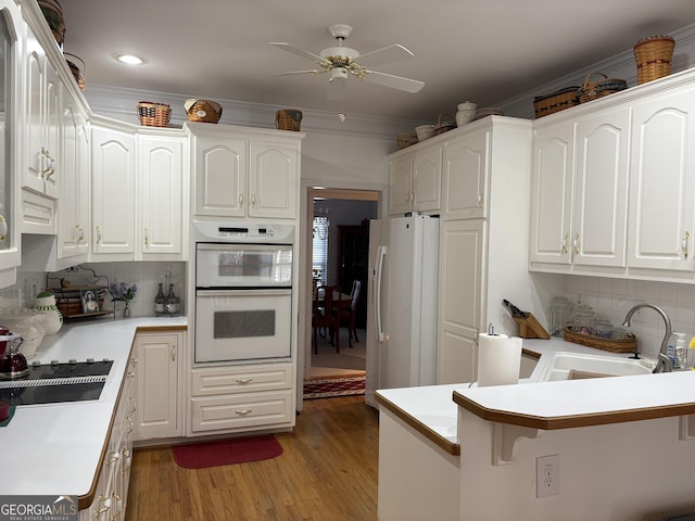 kitchen with white cabinetry, white appliances, light wood finished floors, and a sink