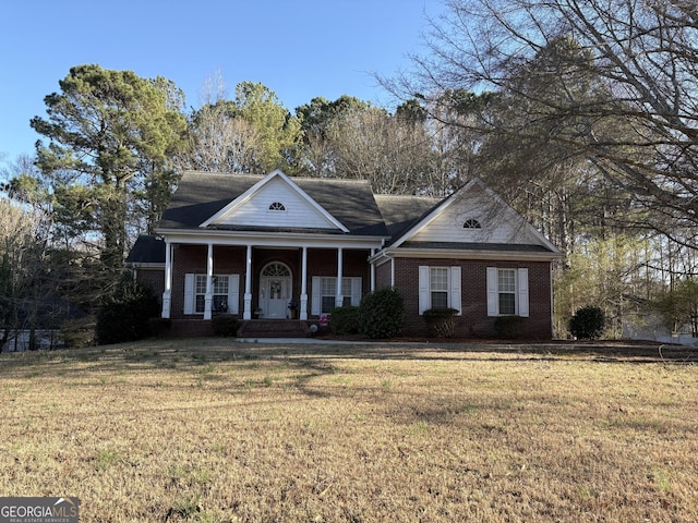 greek revival house featuring brick siding, covered porch, and a front yard