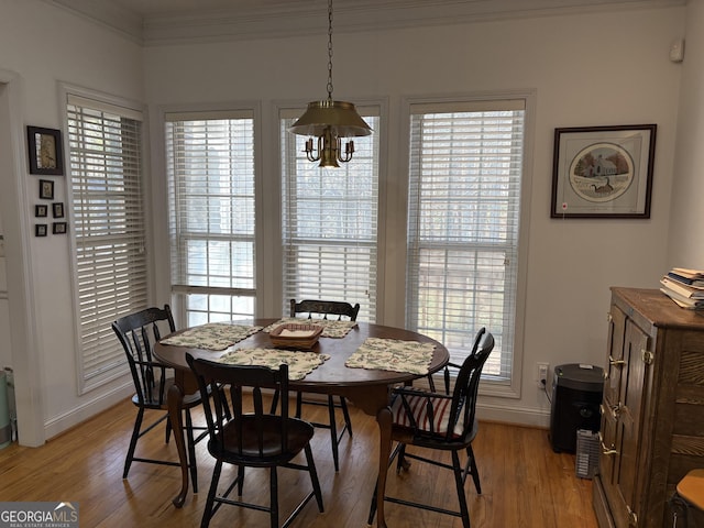 dining space with baseboards, crown molding, and light wood-style floors