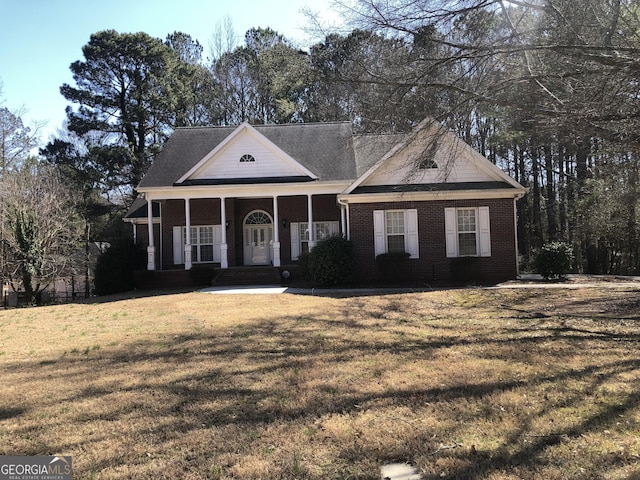 neoclassical / greek revival house featuring brick siding, covered porch, and a front lawn