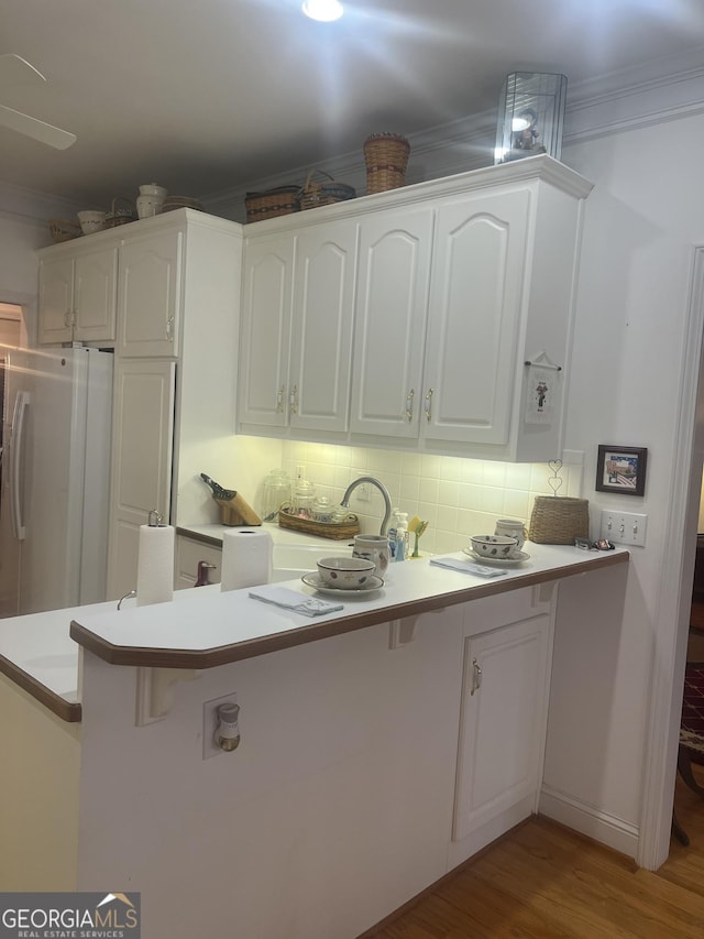 kitchen with decorative backsplash, white cabinetry, and white refrigerator with ice dispenser