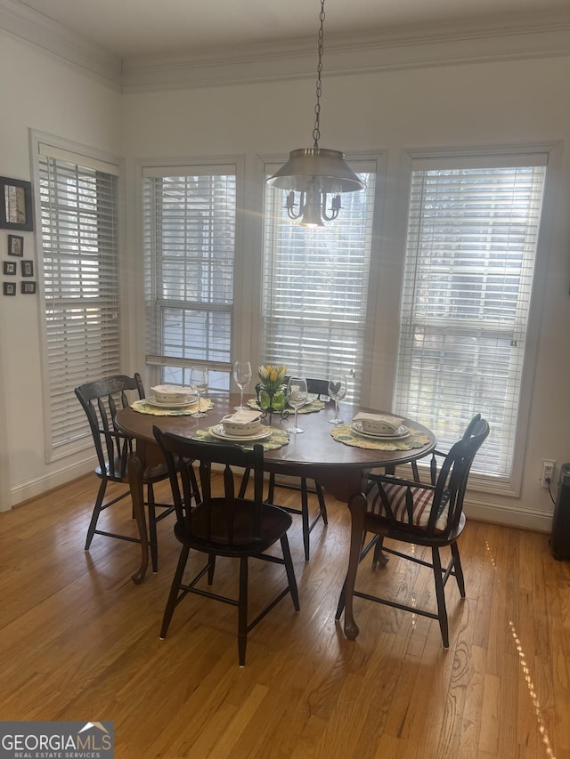 dining space featuring baseboards, crown molding, and light wood finished floors