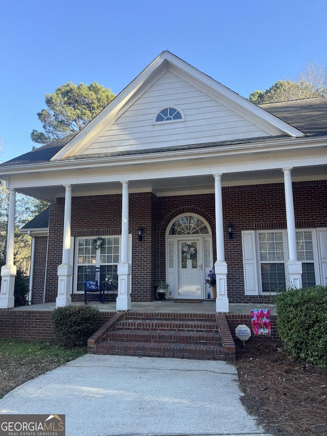 exterior space featuring brick siding and covered porch