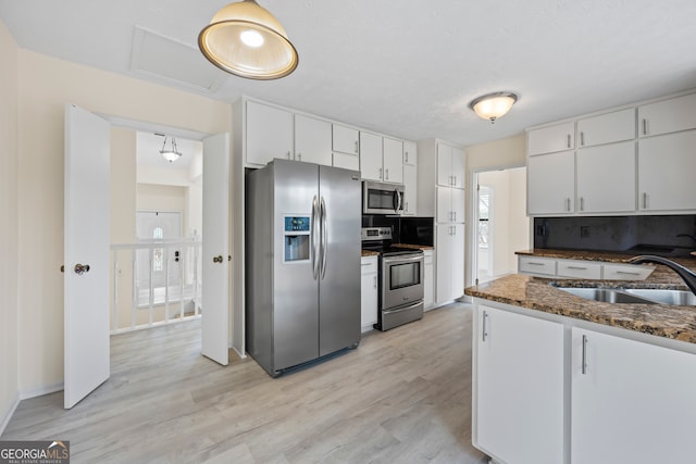 kitchen featuring sink, white cabinetry, dark stone countertops, stainless steel appliances, and decorative backsplash