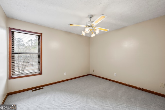 carpeted empty room with ceiling fan and a textured ceiling