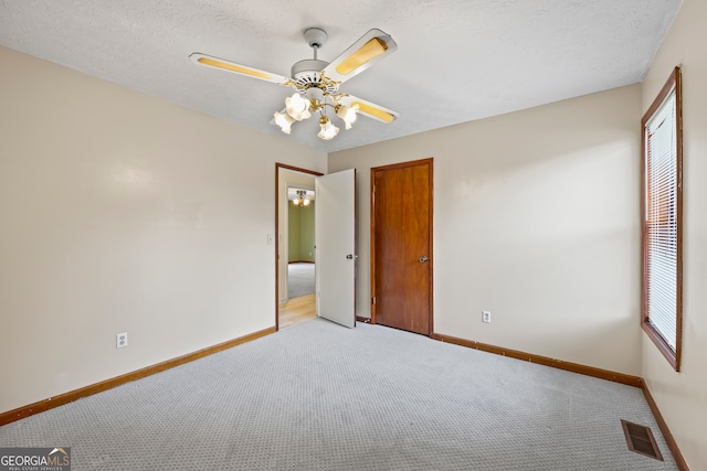 unfurnished bedroom with ceiling fan, light colored carpet, and a textured ceiling