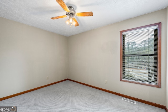 empty room with ceiling fan, carpet, and a textured ceiling