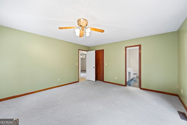 unfurnished bedroom featuring ceiling fan, light colored carpet, a textured ceiling, and ensuite bath