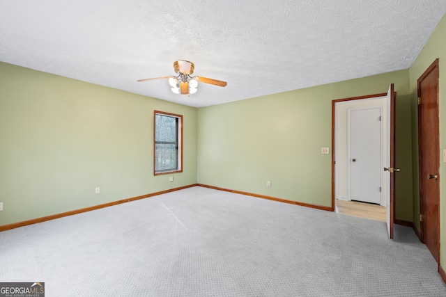 spare room with ceiling fan, light colored carpet, and a textured ceiling