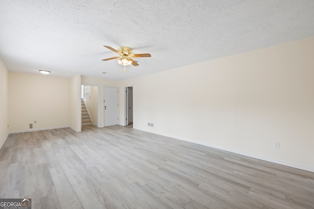 spare room featuring ceiling fan, light hardwood / wood-style floors, and a textured ceiling