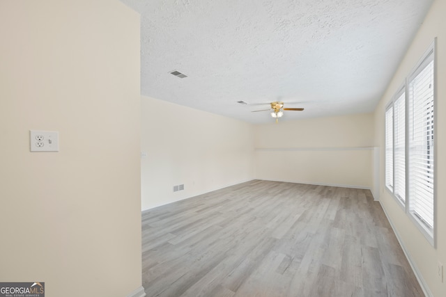 unfurnished room with ceiling fan, light hardwood / wood-style flooring, and a textured ceiling