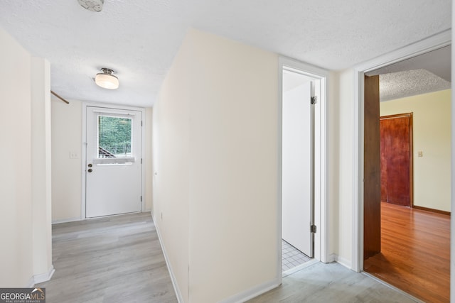 corridor featuring a textured ceiling and light wood-type flooring