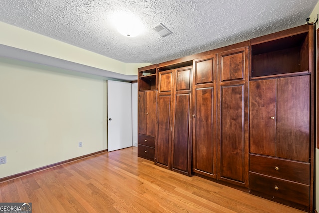 unfurnished bedroom featuring a textured ceiling and light wood-type flooring