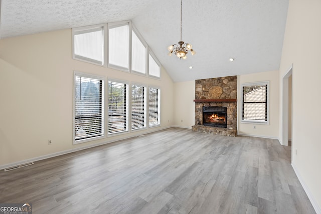 unfurnished living room featuring plenty of natural light, a fireplace, a textured ceiling, and light wood-type flooring