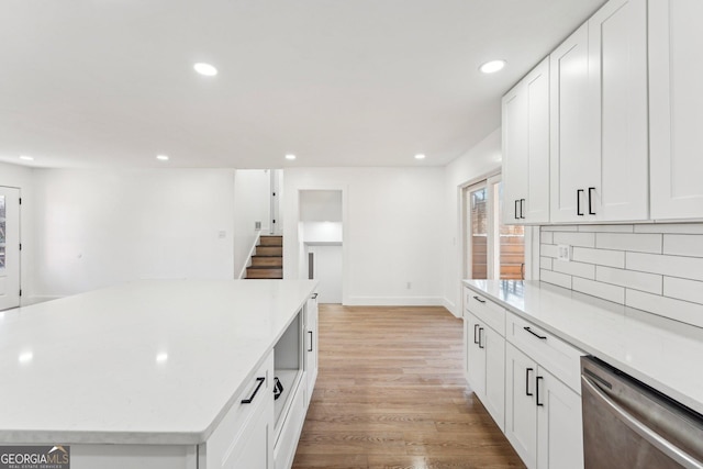 kitchen with dishwasher, white cabinets, decorative backsplash, a center island, and light wood-type flooring