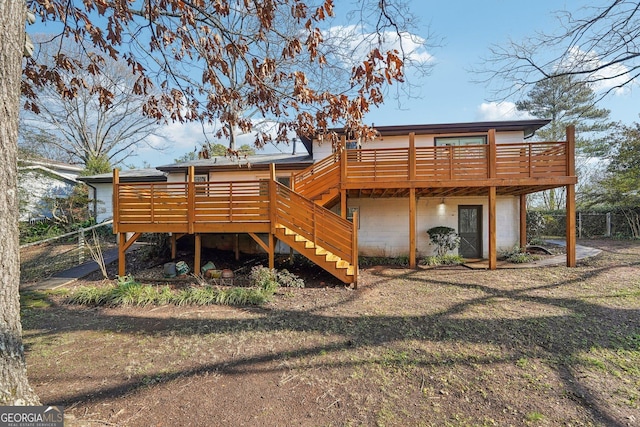 rear view of house featuring a wooden deck and a lawn