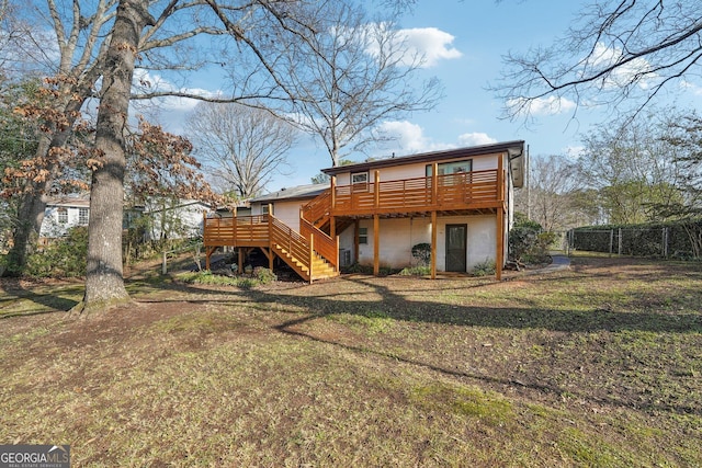 back of property featuring a deck and a lawn