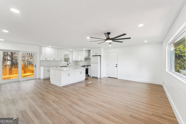 kitchen with stainless steel stove, white cabinetry, white refrigerator, tasteful backsplash, and wall chimney exhaust hood