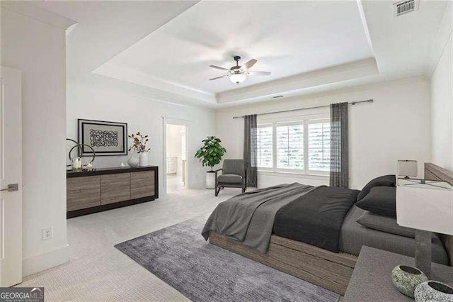 bedroom with ceiling fan, a tray ceiling, and light carpet