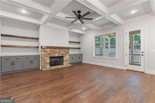 unfurnished living room featuring coffered ceiling, a stone fireplace, dark wood-type flooring, and beam ceiling